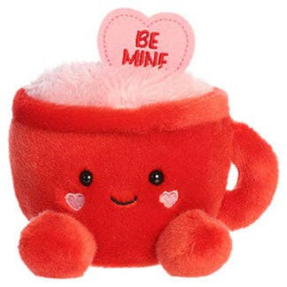 A red plush coffee mug character toy with embroidered facial features, small pink heart accents, and a pink heart-shaped topper that says 'BE MINE' in red text, shown on a plain white background.