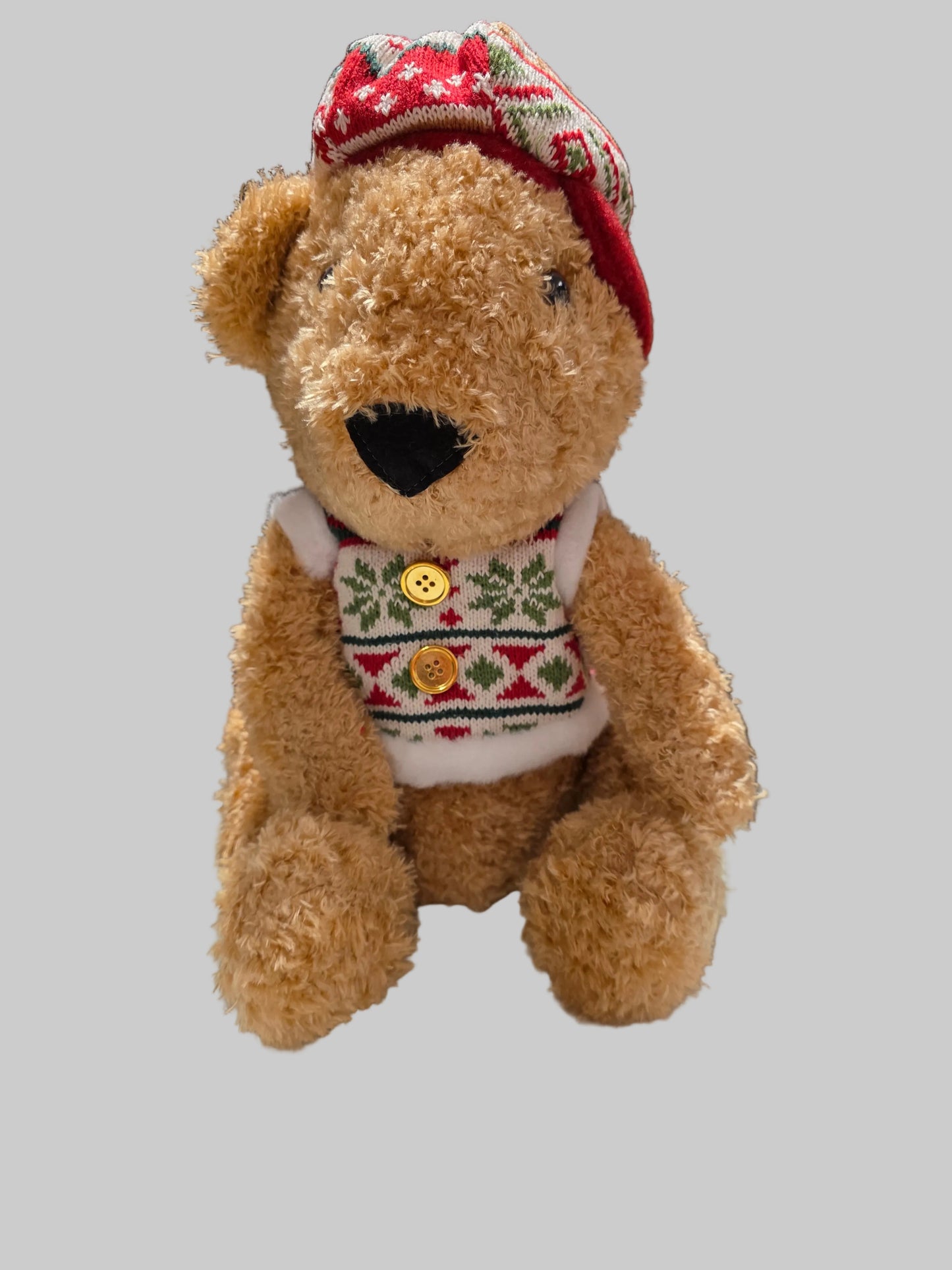 Teddy bear wearing a festive sweater and hat on a gray background