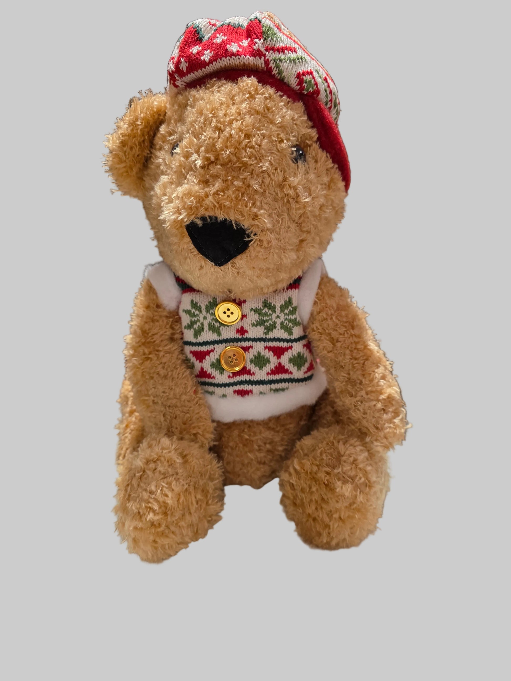 Teddy bear wearing a festive sweater and hat on a gray background