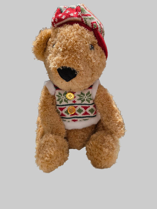Teddy bear wearing a festive sweater and hat on a gray background