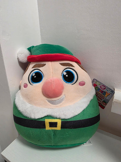 Plush toy resembling a character with a green outfit and red hat on a white surface.