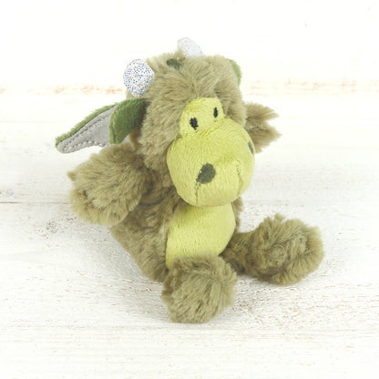 Green plush dragon toy on a light wooden surface