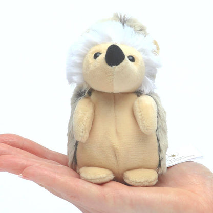 Small plush hedgehog toy held in a hand against a white background